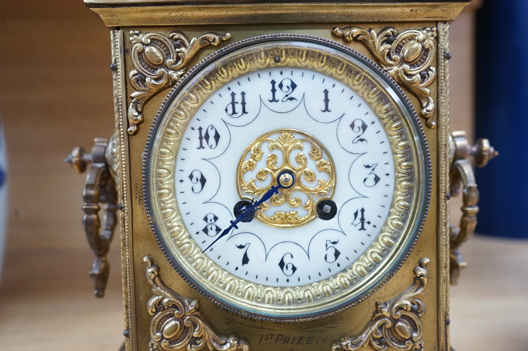 A decorative brass mantel clock with urn surmount, with 1st prize engraved panel, 41cm high
